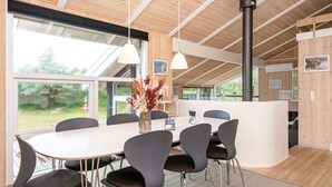 A modern dining area with a round table, black chairs, and a vase of dried flowers. - 8 Person Holiday Home in Lokken (Lokken)