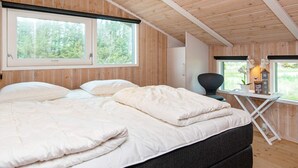 A bedroom with a bed, two windows, a desk, and a chair. - 8 Person Holiday Home in Lokken (Lokken)