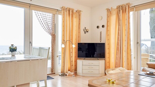 A modern living room with a TV, a dining table, and a view of the sea. - 4 Star Holiday Home in Allinge (Allinge)