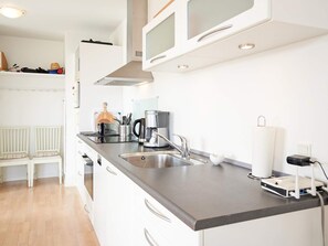 A modern kitchen with a stainless steel sink, a coffee maker, and a white countertop.