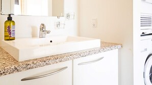 A bathroom with a white sink, a mirror, a bottle of hand soap, and a washing machine. - 4 Star Holiday Home in Allinge (Allinge)