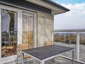 Ein Balkon mit Tisch und Stühlen, eine Schiebetür und Blick auf die Landschaft.