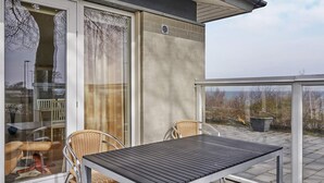 A balcony with a table and chairs, a sliding glass door, and a view of the landscape. - 4 Star Holiday Home in Allinge (Allinge)