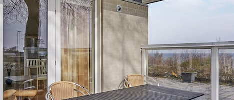 A balcony with a table and chairs, a sliding glass door, and a view of the landscape.