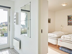 A room with a bed, a radiator, a window with a view of the outside, and a door.