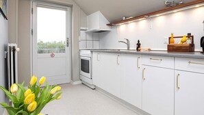 A modern kitchen with white cabinets, a built-in oven, and a wooden countertop. - 6 Person Holiday Home in Blavand (Blavand)