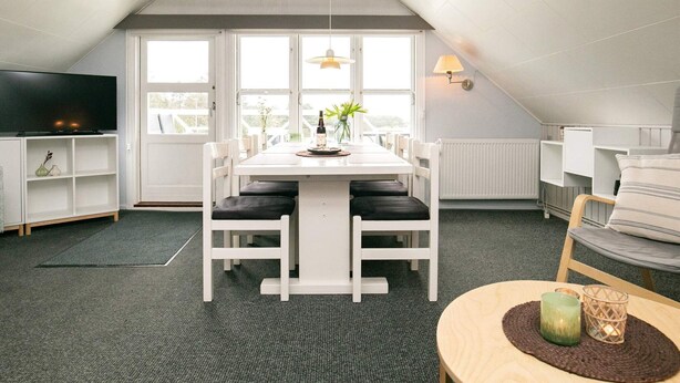 A modern loft apartment with a dining area, a TV, and a cozy seating space. - 6 Person Holiday Home in Blavand (Blavand)