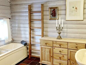 Relax in this cozy bathroom with a bathtub, wooden vanity, and ample storage.