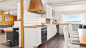 Een landelijke keuken met witte kastjes, een fornuis en een groot raam met uitzicht.