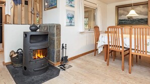 A cozy room with a stone fireplace, wooden furniture, and artwork on the walls. - 6 Person Holiday Home in Haarby (Haarby)