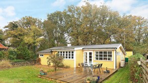 A yellow house with a wooden deck, a small garden, and a large window. - 6 Person Holiday Home in Haarby (Haarby)