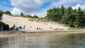 A beach with tents and people, a river, and trees.