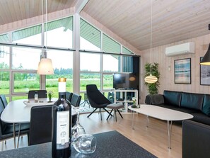 Un intérieur moderne comprenant une table à manger, des chaises, un canapé et un téléviseur.