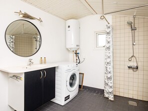 Une petite salle de bain équipée d’un lave-linge, d’un miroir, d’un porte-serviettes et d’une douche.