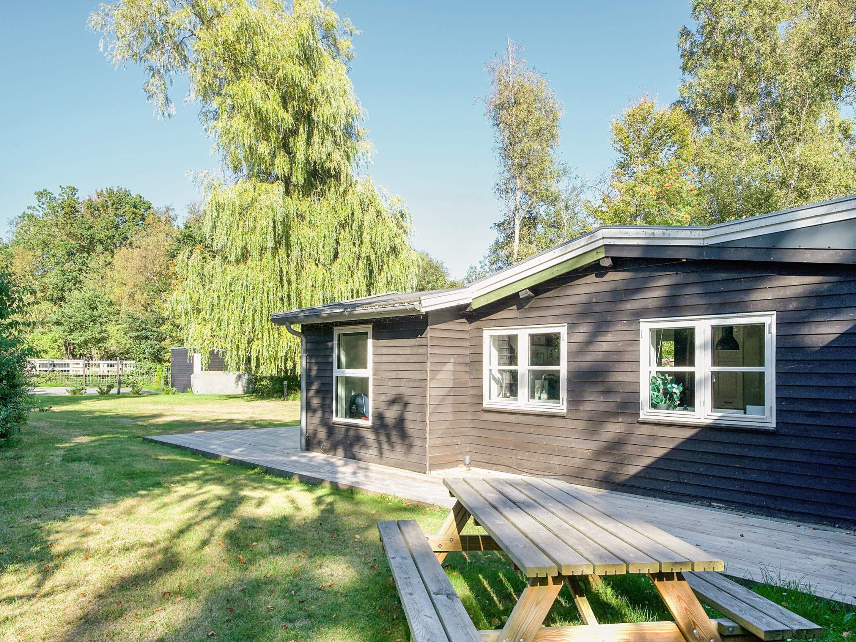 A single-story house with a dark exterior, a front porch, and a wooden deck.