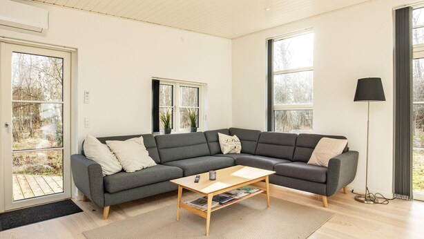 A modern living room with a grey sectional sofa, a wooden coffee table, and a floor lamp.