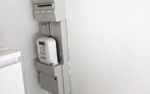 Un tableau électrique blanc, doté d’un panneau de commande et d’un compteur.