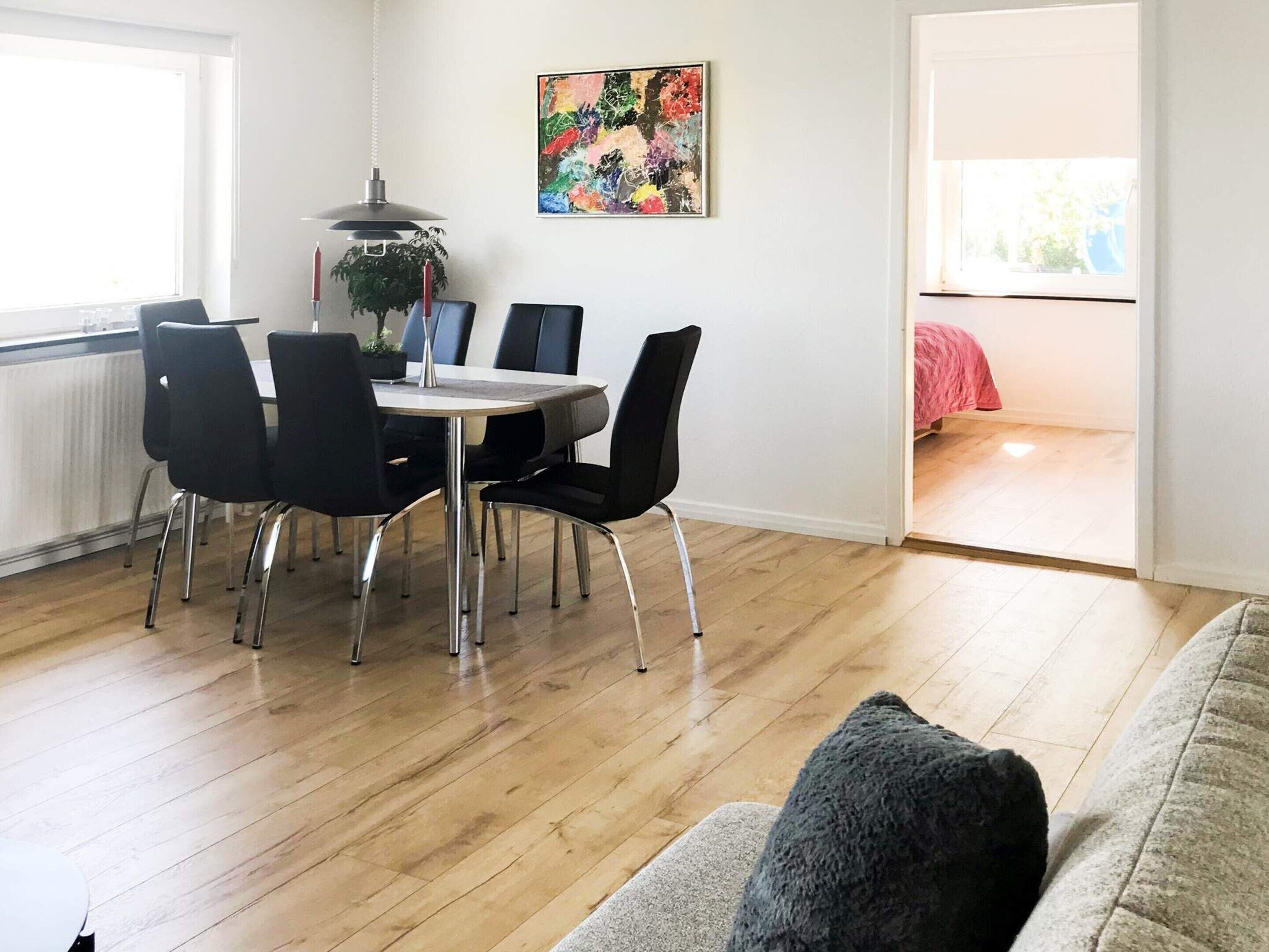 Un coin repas avec une table ronde et des chaises, un luminaire suspendu et un tableau au mur.