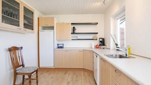 A compact kitchen with wooden cabinets, a built-in dishwasher, and a window providing natural light. - 4 Person Holiday Home in Fjerritslev (Fjerritslev)