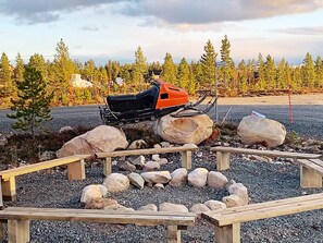 A snowmobile on a gravel path with wooden benches and rocks, surrounded by trees. - 4 Star Holiday Home in Idre (Idre)