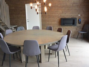 A conference room with a large round table, grey upholstered chairs, a modern light fixture, and a flat-screen TV mounted on the wall. - 4 Star Holiday Home in Idre (Idre)