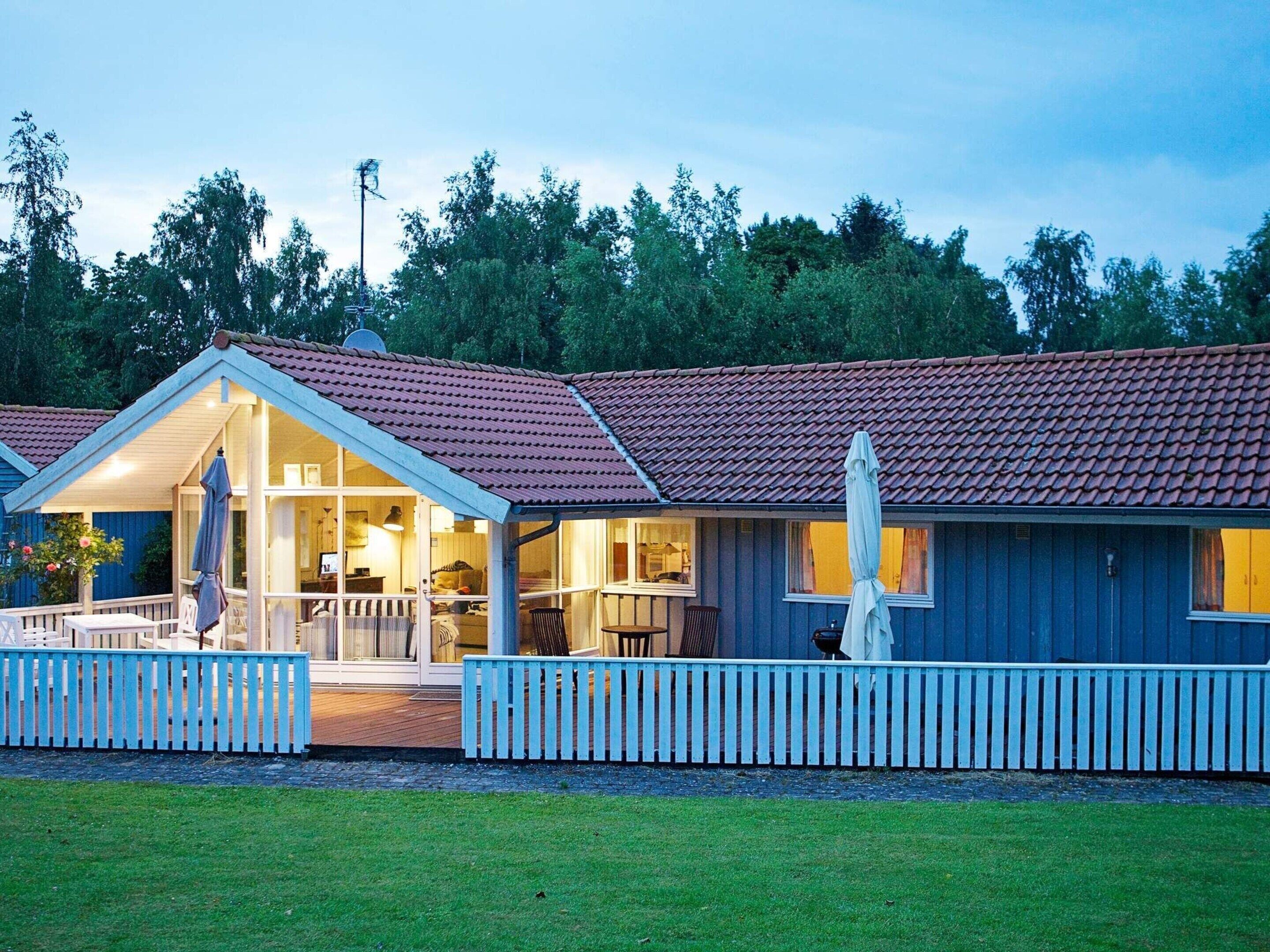 A two-story building with a red-tiled roof, a covered porch with a white picket fence, and a well-maintained lawn.