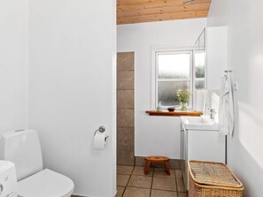 A small, bright bathroom with a white toilet, a sink, and a window. - 8 Person Holiday Home in Hadsund (Hadsund)