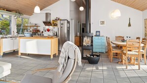 A modern kitchen with a central island, a dining area with wooden chairs, and a large stove. - 8 Person Holiday Home in Hadsund (Hadsund)