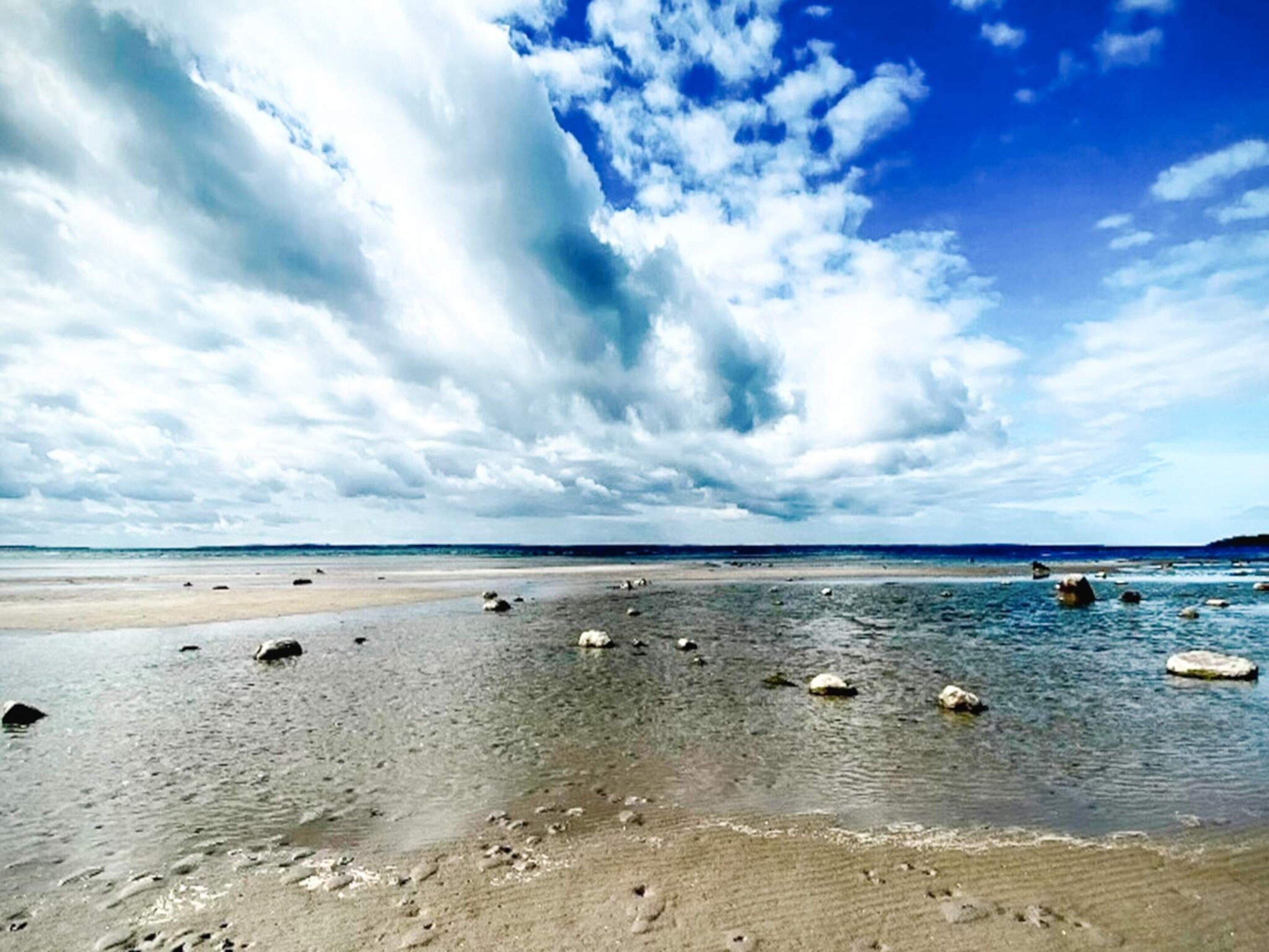 Ein Strand mit verstreuten Steinen und blauem Himmel.
