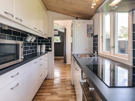 Cocina moderna con microondas, horno y pileta de acero inoxidable.