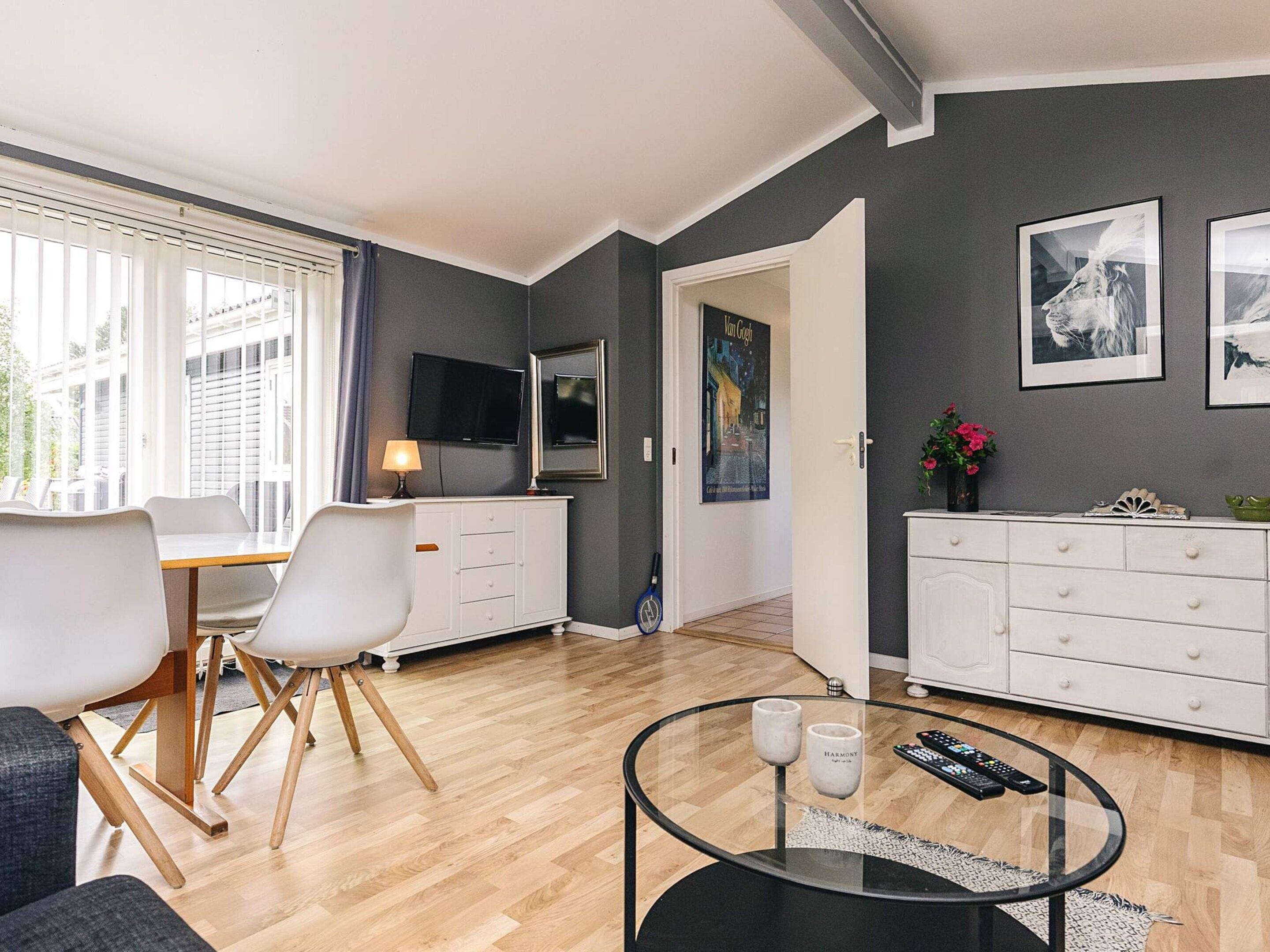 A modern living room with a dining area, a flat-screen TV, and artwork on the walls.