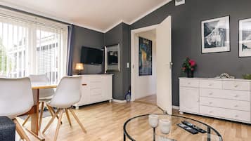 A modern living room with a dining area, a flat-screen TV, and artwork on the walls.