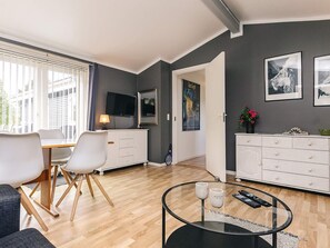 Un saló modern amb zona de menjador, televisió de pantalla plana i obra d'art a les parets.