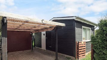 A two-story building with a covered patio area, a garage, and a window with a sign.