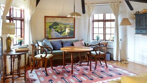 Ein gemütliches Zimmer mit einer Couch, Stühlen, einem Tisch und einem Bild an der Wand.