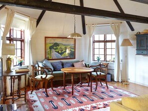 Um quarto aconchegante com sofá, cadeiras, uma mesa e um quadro na parede.