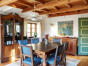Uma sala de jantar com uma mesa e cadeiras de madeira, um armário com portas de vidro e um quadro na parede.