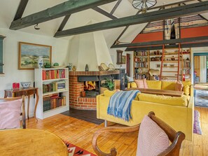 A cozy living room with a fireplace, bookshelves, a yellow sofa, and wooden flooring. - 9 Person Holiday Home in Vig (Vig)