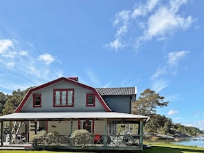 A two-story house with a porch, a small attached structure, and a view of a lake. - 4 Star Holiday Home in Uddevalla (Uddevalla)