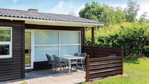 A small house with a patio, a table, and chairs.