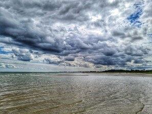 A beach with a wide expanse of water and a cloudy sky. - 6 Person Holiday Home in Hadsund (Hadsund)