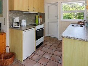 Een kleine keuken met een inbouwoven, een koffiezetapparaat en een spoelbak.