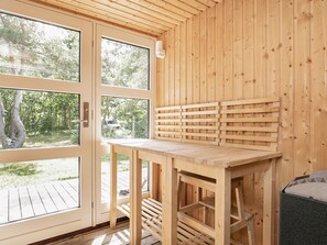 En inredning med träpanel, en bänk och ett bord, stora fönster och utsikt över grönområden utanför.