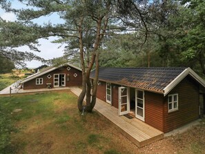 A wooden cabin with a sloped roof, a porch, and a small deck area.