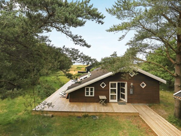 A wooden cabin with a sloped roof, a deck, and a small table.