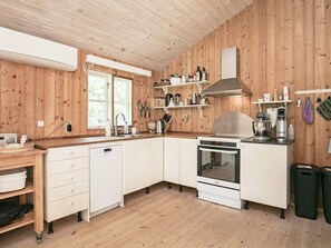 A modern kitchen with wooden walls, white cabinets, a built-in oven, and a coffee machine. - 12 Person Holiday Home in Laeso (Læsø)