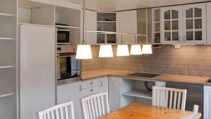 A kitchen with white cabinets, a wooden table, and pendant lights. - 8 Person Holiday Home in Snillfjord (Orkland)