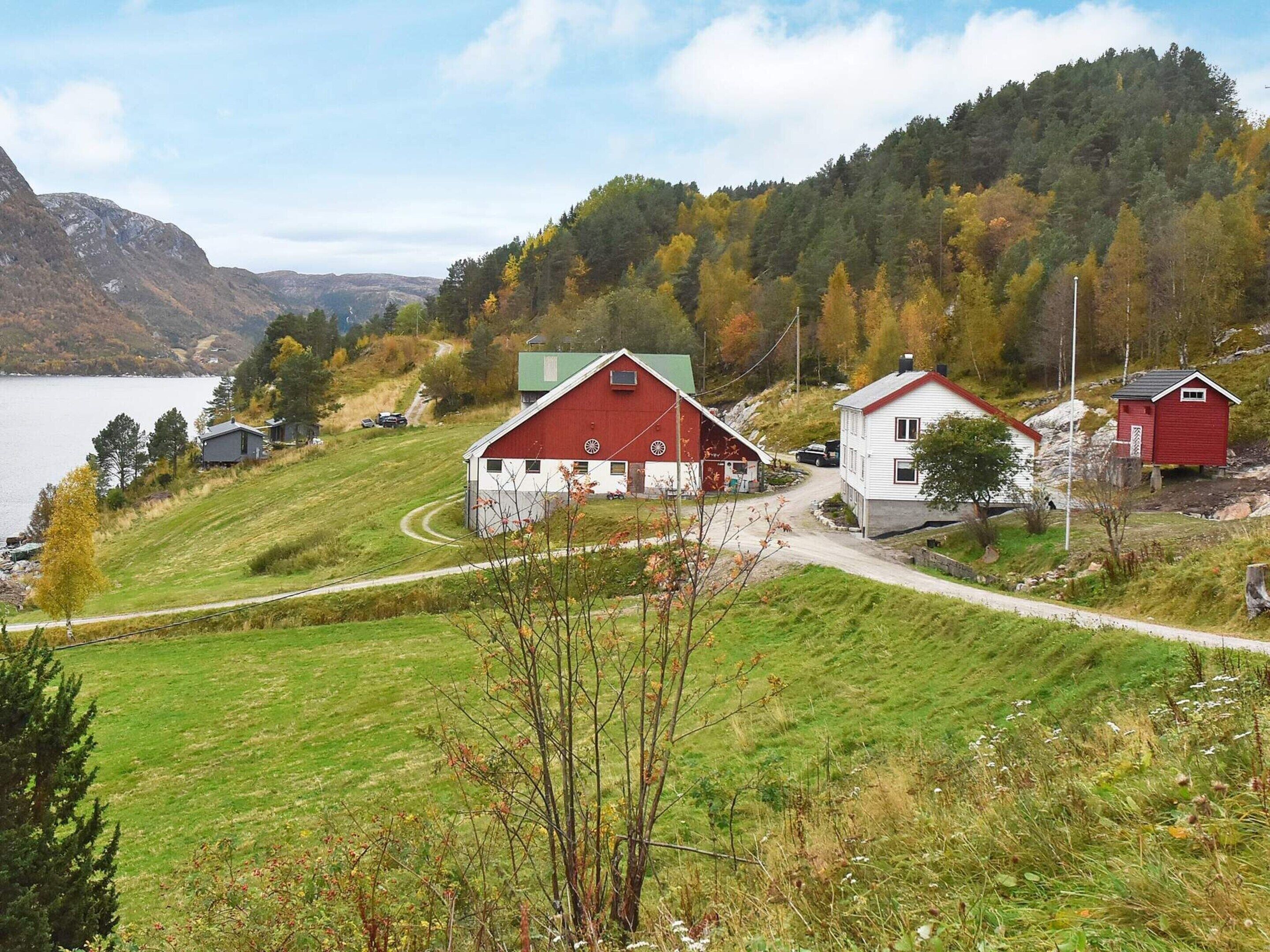 A rural landscape with a red barn, a white house, and a small red shed.