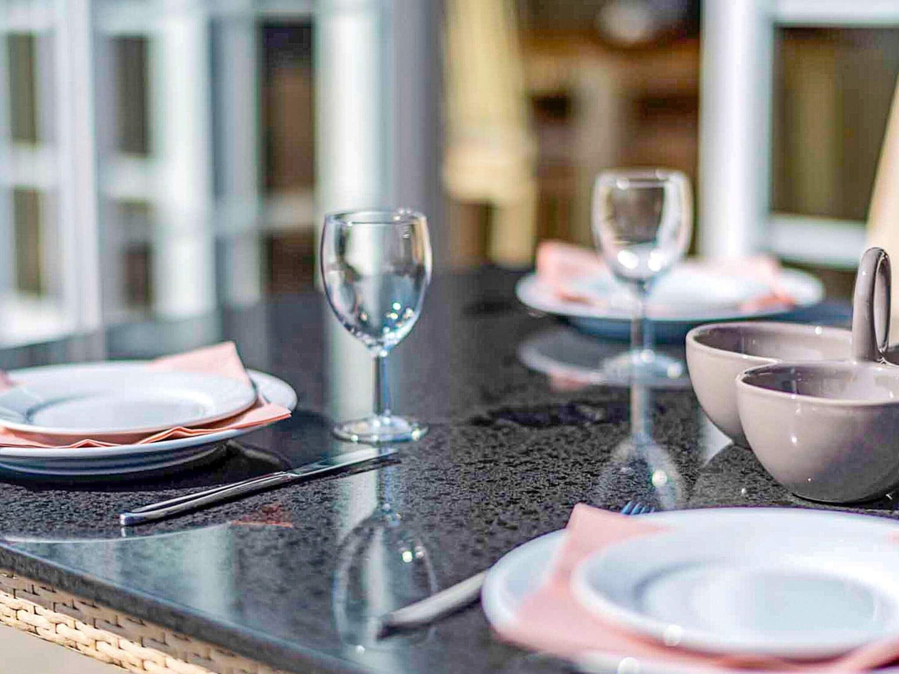 A table set with plates, bowls, and wine glasses, indicating a dining area.