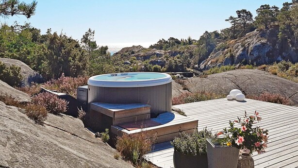 A hot tub on a wooden deck with a view of the ocean and hills. - 4 Star Holiday Home in Sondeled (Risør)